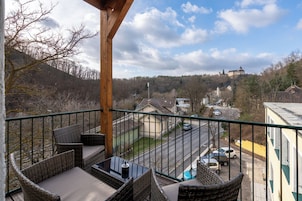 A balcony with wicker furniture overlooking a residential area and a distant castle.