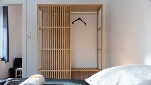 Un dormitorio con cama, armario de madera y perchero.