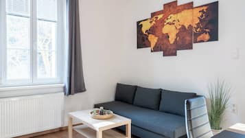 A modern living room with a grey sofa, a small white table, and a world map artwork on the wall.