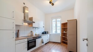 Una cocina moderna con armarios blancos, horno integrado y una ventana con persianas.