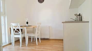 A small, bright kitchen with white cabinetry, a wooden table, and two white chairs.