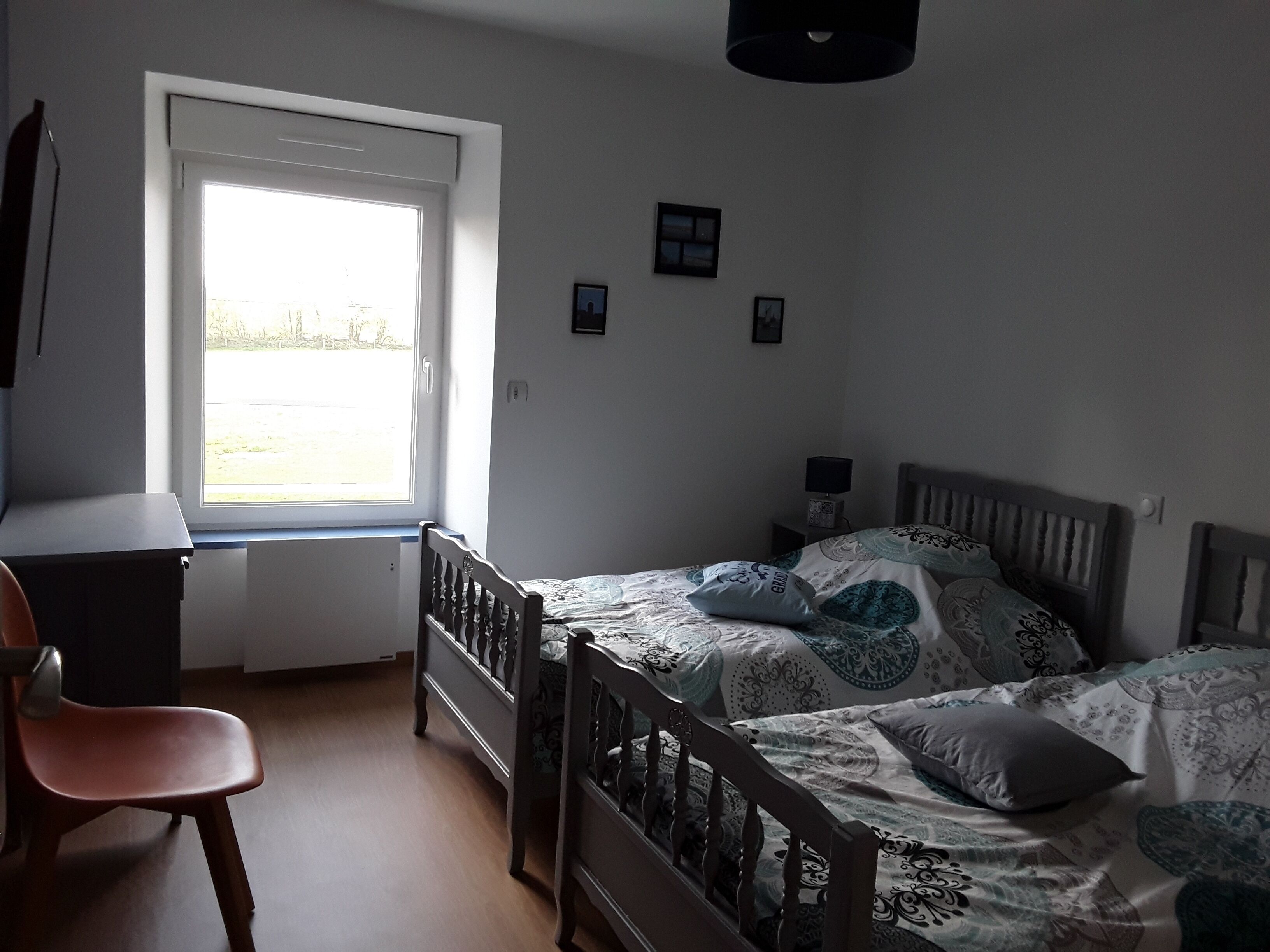 A bedroom with a single bed, a desk, and a chair.