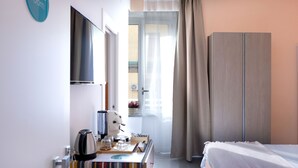 A hotel room with a bed, a desk with a coffee maker, a TV, and a wardrobe. - Sun&City Naples (Naples)