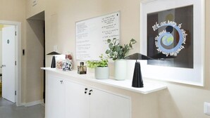 A reception area with a white counter, a framed welcome sign, a bulletin board, and a potted plant. - Sun&City Naples (Naples)