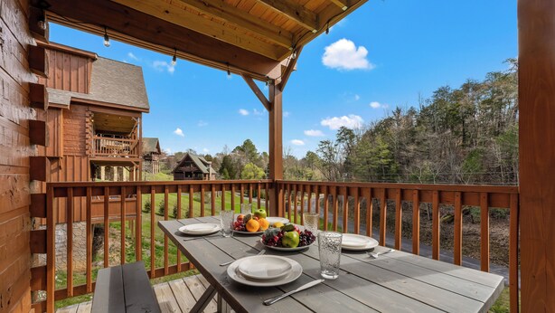 A wooden deck with a picnic table set for two, surrounded by a wooden railing. - Couples Refuge by Ghosal Luxury Lodging (Sevierville)