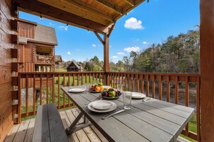 A wooden deck with a picnic table set for two, surrounded by a wooden railing.