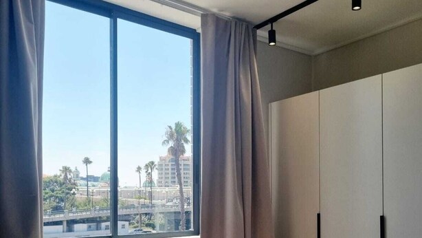 A hotel room with a large bed, a wardrobe, and a window with curtains. - on Park by Smart City Stays (Cape Town)