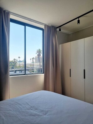 Une chambre d’hôtel avec un grand lit, une armoire et une fenêtre avec des rideaux.