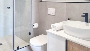 A modern bathroom with a glass-enclosed shower, a toilet, a sink, and a mirror. - on Park by Smart City Stays (Cape Town)