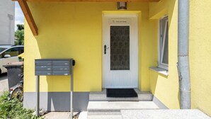 A yellow building with a white door, a mailbox, and a window. - revLIVING Apartments Gars am Kamp (Gars am Kamp)