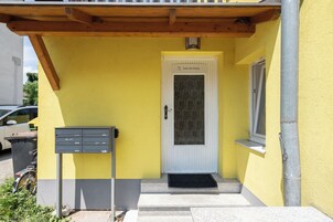 A yellow building with a white door, a mailbox, and a window.