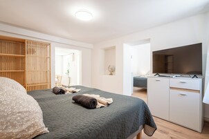 A bedroom with a bed, a TV, a wardrobe, and a desk.