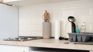 A kitchen with a white tiled backsplash, a stainless steel range hood, a kettle, and a coffee maker. - revLIVING Apartments Gars am Kamp (Gars am Kamp)
