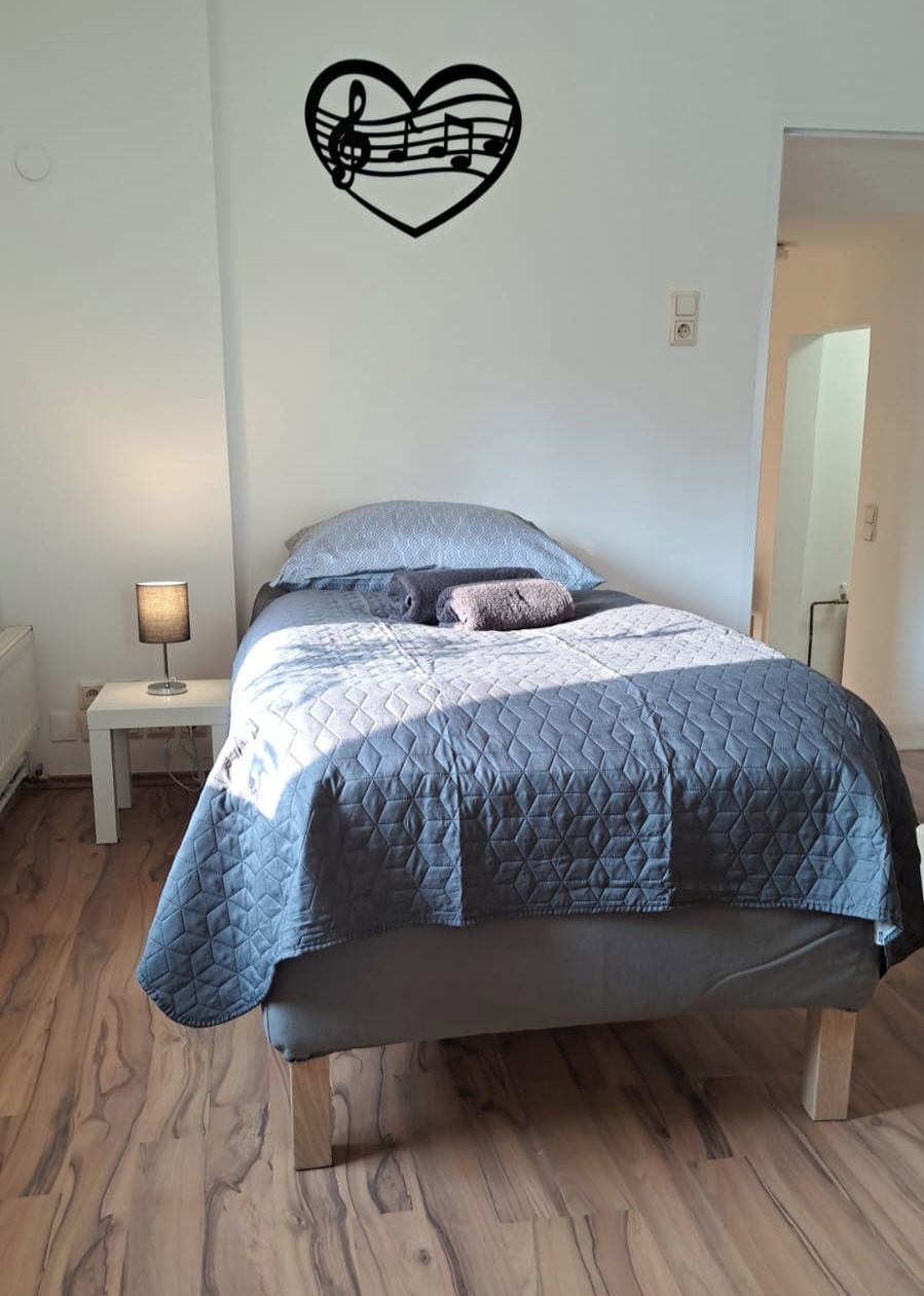 A bedroom with a bed, a nightstand, a lamp, and a wall decal.