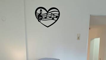 A bedroom with a bed, a nightstand, a lamp, and a wall decal.