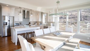 Une cuisine moderne avec des meubles blancs, des appareils en acier inoxydable et un grand îlot central doté de sièges.