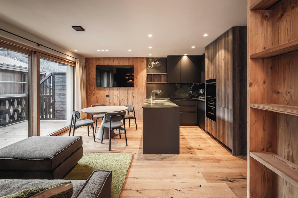 Une cuisine moderne avec des meubles en bois, un îlot central et un coin repas comprenant une table ronde et des chaises.