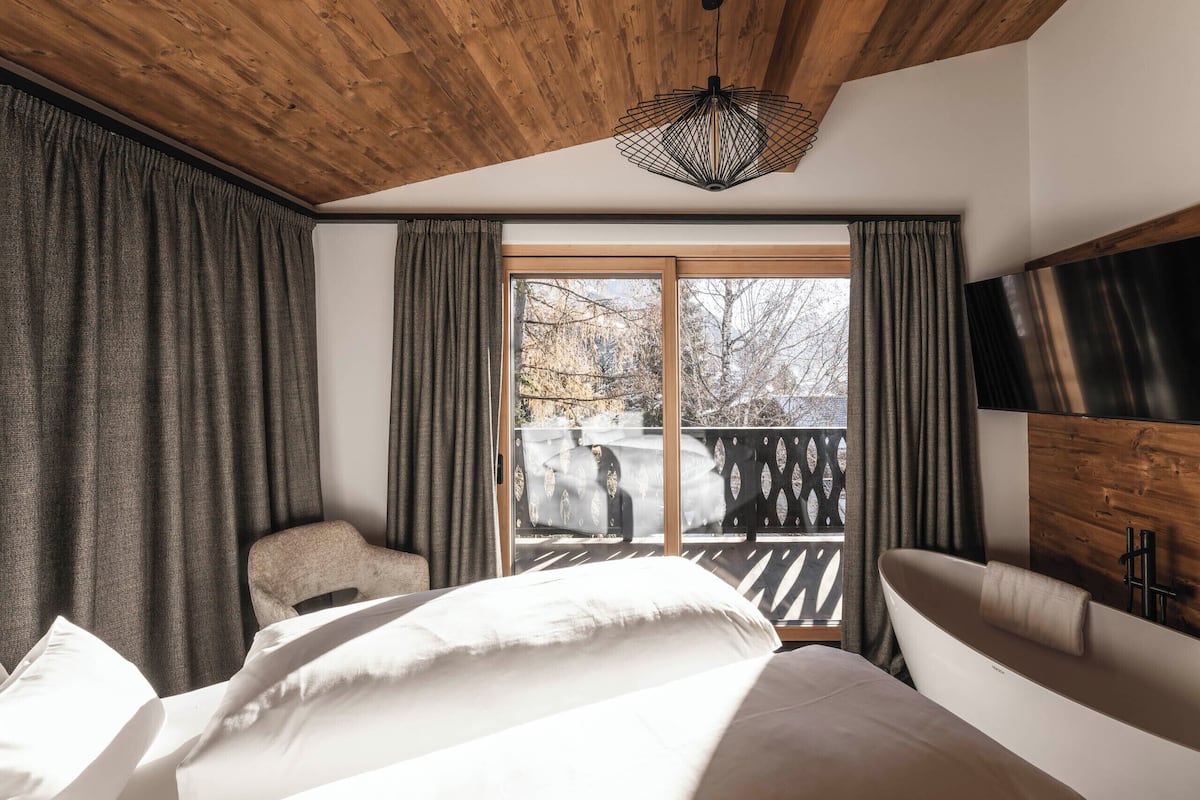 Une chambre avec un grand lit, un plafond en bois, une fenêtre avec des rideaux et une vue sur un balcon.