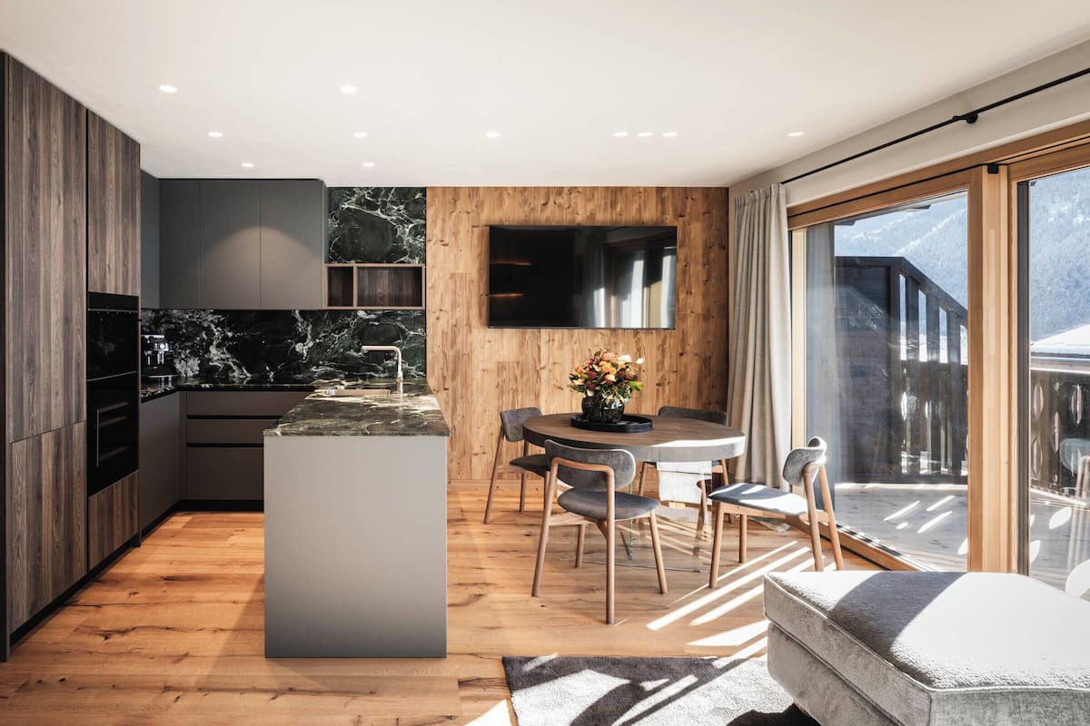 Une cuisine moderne dotée d’un îlot central, de meubles en bois et d’une grande fenêtre offrant une vue sur l’extérieur.