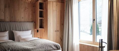Un dormitorio con paneles de madera, un ventanal grande, una estantería empotrada y una bañera independiente.
