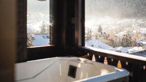 A room with a large window overlooking a snowy landscape and a hot tub. - DISTINCTIVE LUXURY DOLOMITI APARTMENTS TERRE71 (Marebbe)