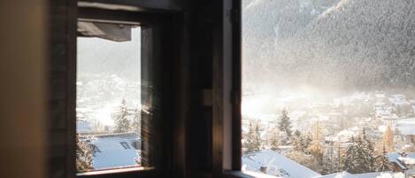 A room with a large window overlooking a snowy landscape and a hot tub.