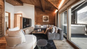 A modern living room with a wooden ceiling, a large window with a mountain view, a sofa, a coffee table, and a TV. - DISTINCTIVE LUXURY DOLOMITI APARTMENTS TERRE71 (Marebbe)