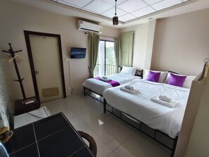 A hotel room with two beds, a TV, an air conditioner, and a window with curtains. - TC House And Cafe (Chiang Mai)