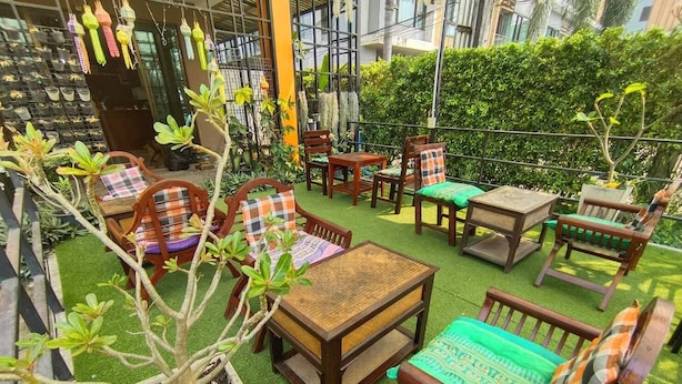 An outdoor seating area with wooden furniture and potted plants. - TC House And Cafe (Chiang Mai)
