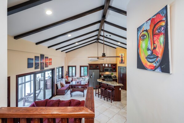 A spacious kitchen with a large island, a dining area with a wooden bench, and a vibrant abstract painting on the wall.
