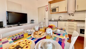 Et spiseområde med et bord dækket til morgenmad, inklusive croissanter, småkager og en tekedel.