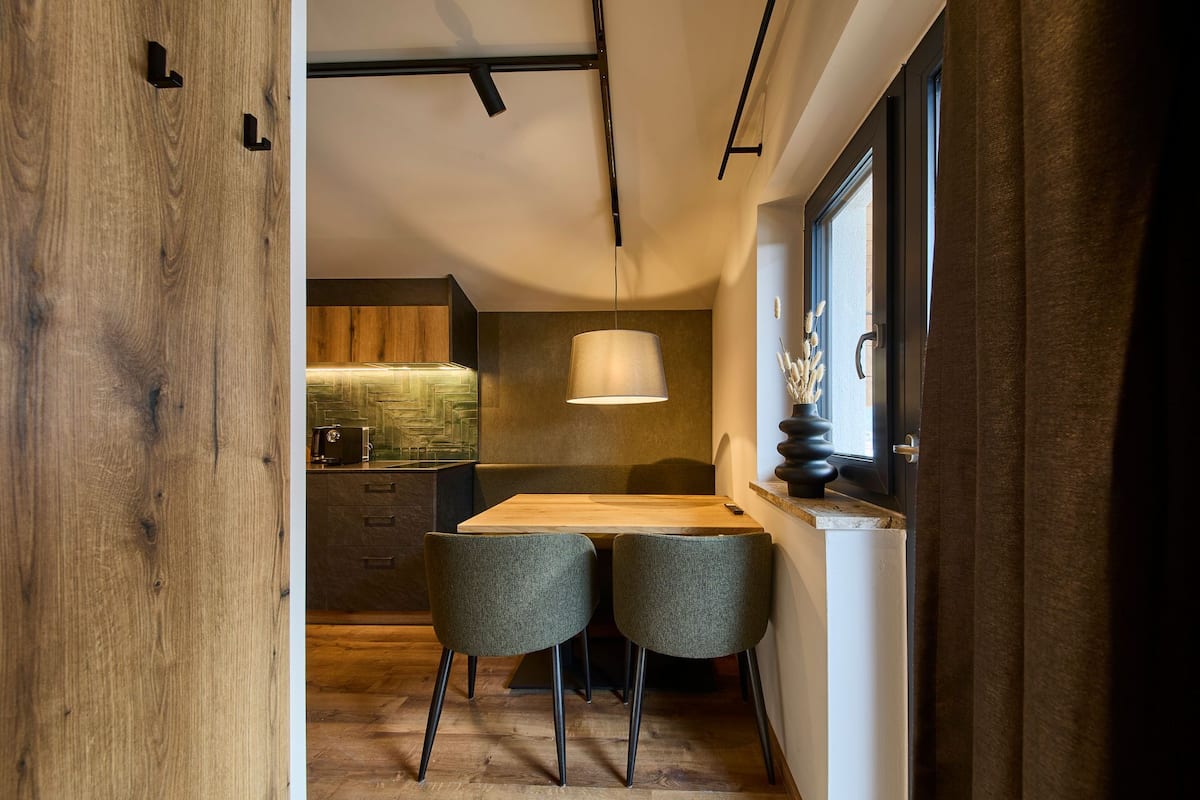Une cuisine moderne avec des meubles en bois, une cuisinière encastrée et un luminaire suspendu.