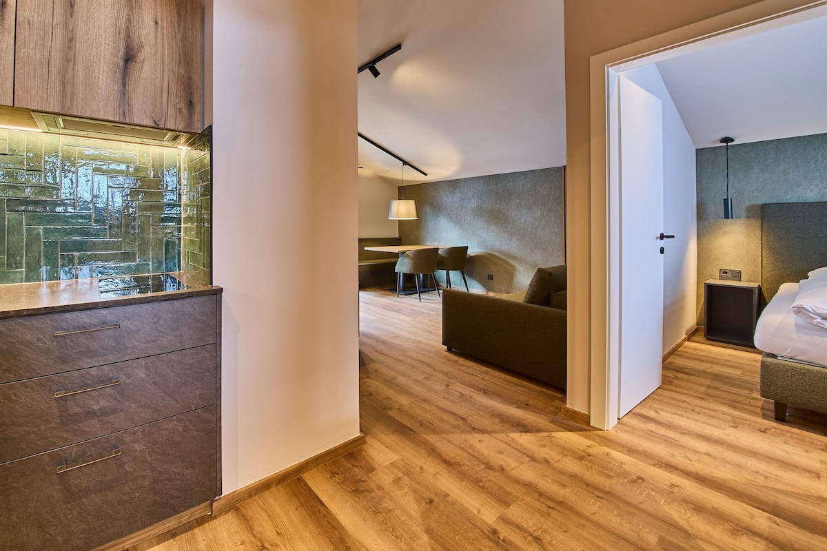 Une chambre d’hôtel moderne avec un plancher en bois, un coin repas comprenant une table et des chaises, un canapé et un lit avec une table de chevet.