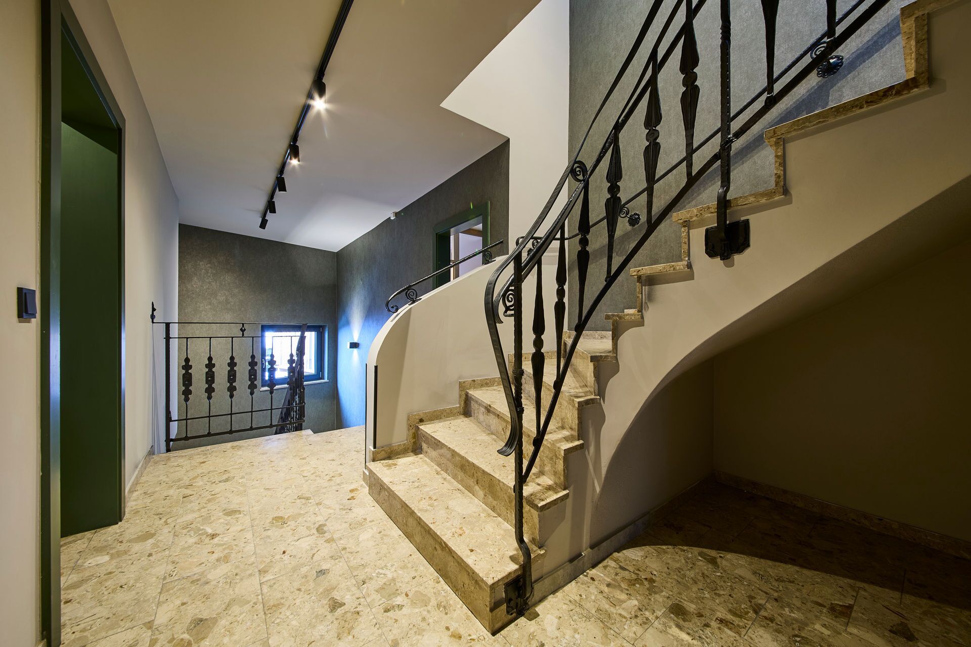 A modern interior with a marble staircase, a metal railing, and a skylight.