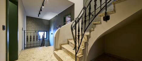 A modern interior with a marble staircase, a metal railing, and a skylight.