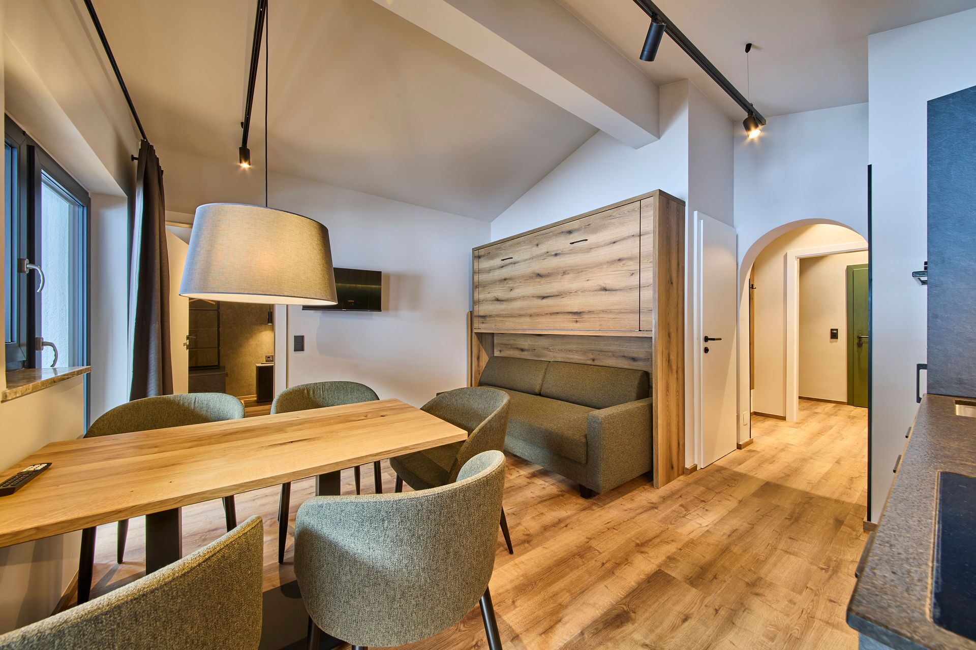 A modern interior with a wooden dining table, cushioned chairs, a large lamp, and a wooden accent wall.