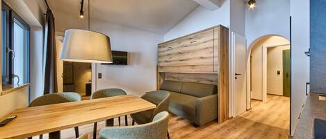 A modern interior with a wooden dining table, cushioned chairs, a large lamp, and a wooden accent wall.