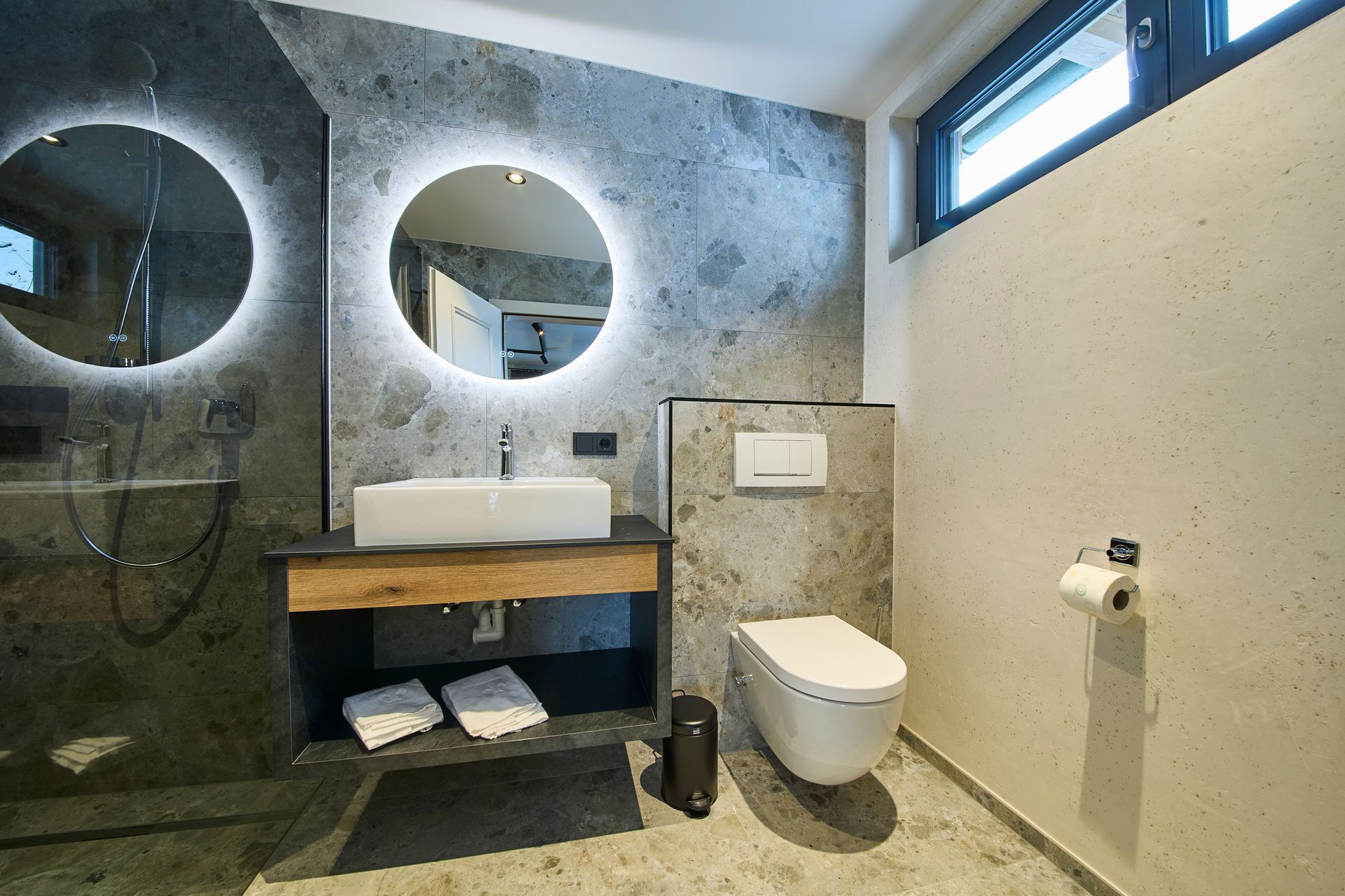Ein modernes Badezimmer mit einem großen Spiegel, einem Waschbecken, einer Toilette und einer Dusche.
