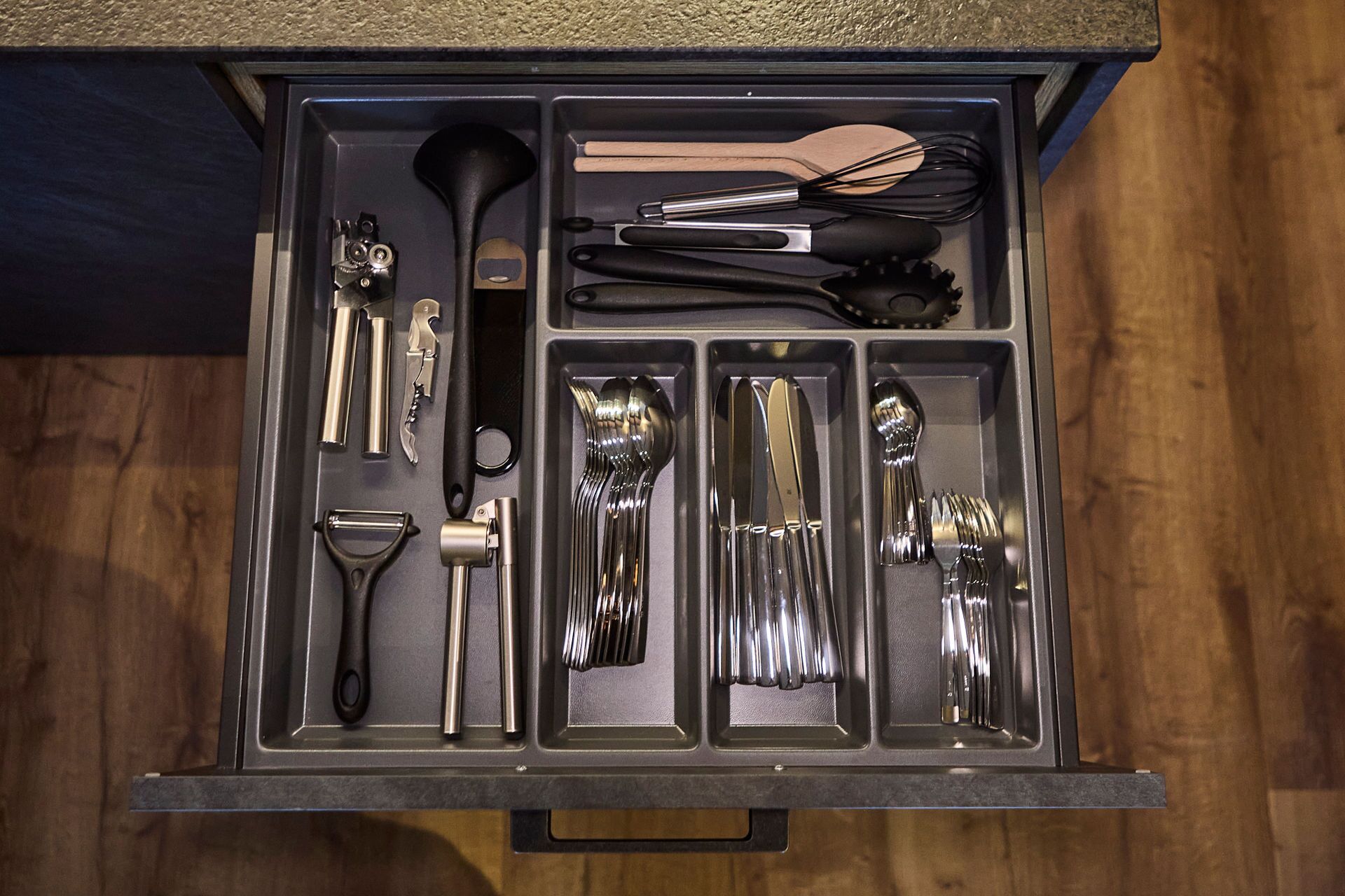 A drawer containing various kitchen utensils including a whisk, spatula, and tongs.