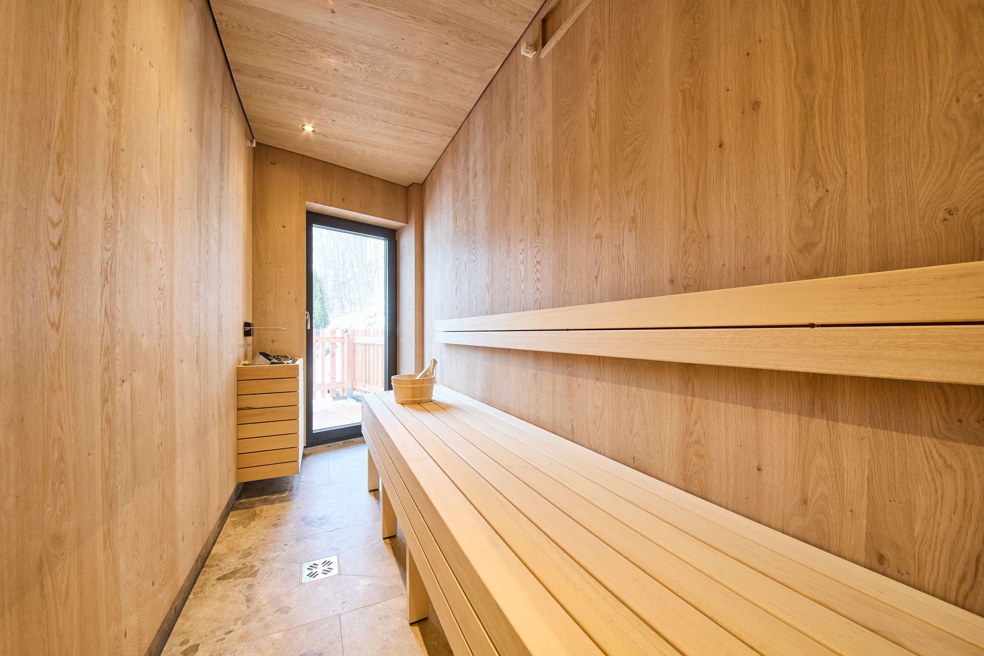 A wooden interior with benches and a door leading outside.