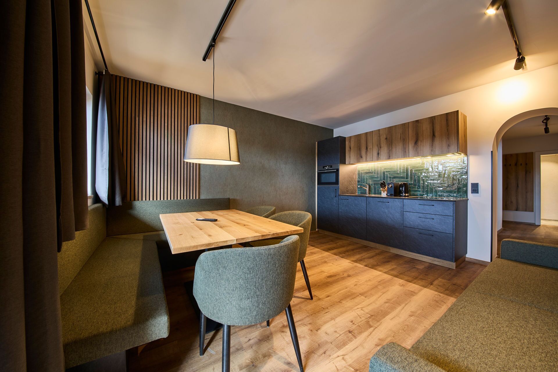 A modern kitchen with a built-in oven and a dining area with a wooden table and chairs.
