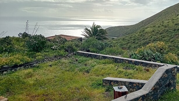 A stone wall with a curved bench, lush greenery, and a view of the sea. - El Lomito - Elegant Countryside Home, El Hierro (Villa de Valverde)