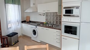 A compact kitchen with a washing machine, microwave, and a small dining area. - El Lomito - Elegant Countryside Home, El Hierro (Villa de Valverde)