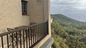 A balcony with a table and chairs, overlooking a mountainous landscape. - El Lomito - Elegant Countryside Home, El Hierro (Villa de Valverde)