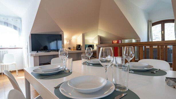 A dining area with a table set for four, including plates, glasses, and cutlery. - La grande Valsassina - Loft (Pasturo)