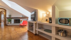 A modern kitchen with a TV, coffee maker, and microwave. There is a red chair and a plant on the counter. - La grande Valsassina - Loft (Pasturo)