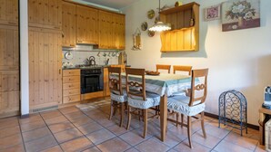 Una cocina con armarios de madera, una estufa y una mesa de comedor con sillas.