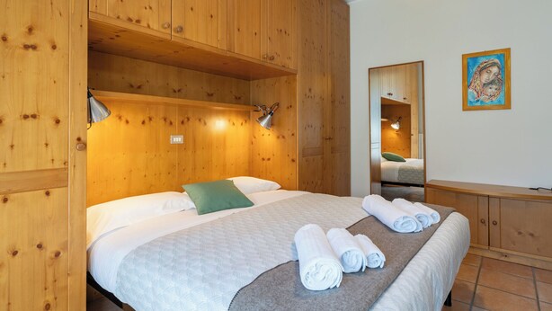 Una habitación de madera con una cama, un espejo y un cuadro en la pared.