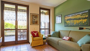 Una sala de estar acogedora con una pared verde, un sofá, un sillón con un cojín de ciervo y un cuadro de girasoles.