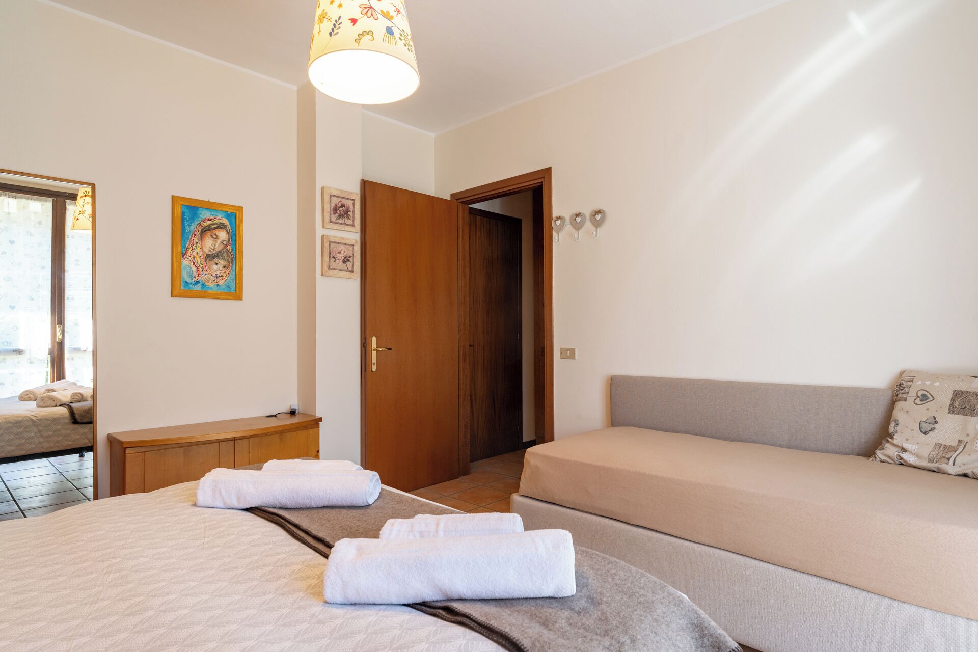 Una habitación de hotel con una cama, un sofá, una mesita de noche de madera y una puerta.